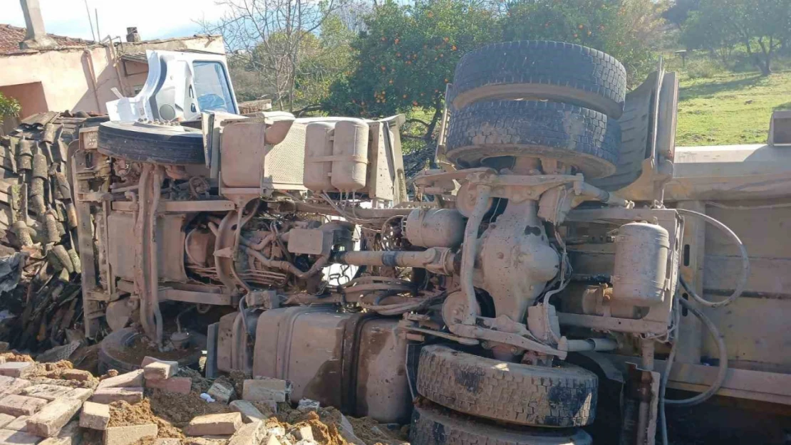 Otobüse çarpan kum yüklü kamyon, bir evin  bahçesine devrildi