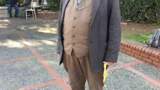 Ayağında körüklü çizmesi, elinden tesbihi düşmüyor